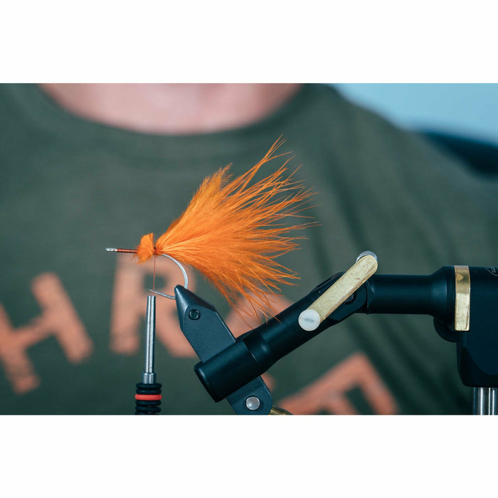 Early stage fly construction with orange fibers and red thread