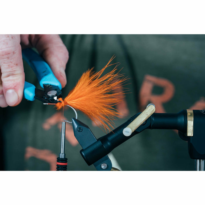 Trimming excess bright orange fibers from silver hook with scissors
