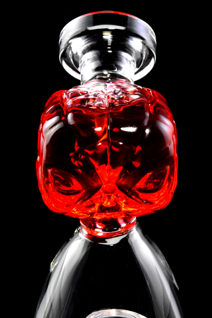 Close-up of red fluid-filled spider hero mouthpiece on a small glass beaker bong, sculpted face detail visible.