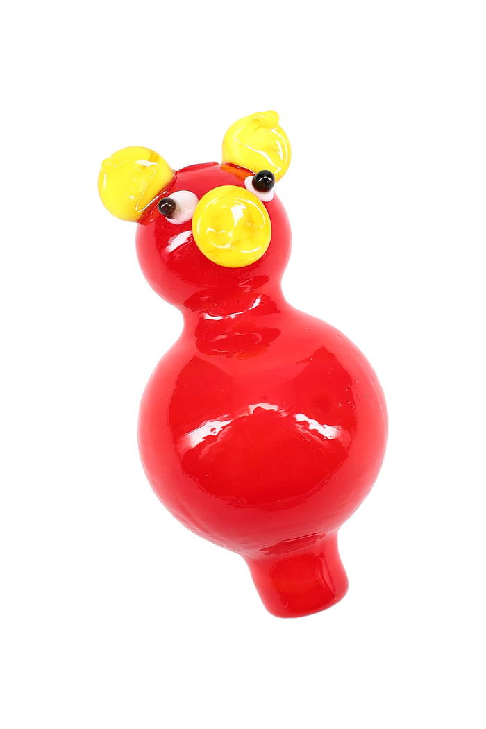 Red pig-shaped glass bubble carb cap with yellow snout and ears; rounded grip and tapered tip for directing airflow on a banger.
